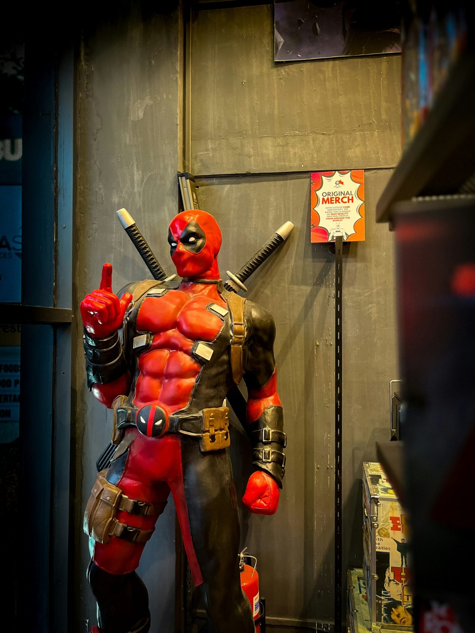 Life-size Deadpool statue standing in a comic merchandise store interior.
